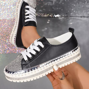 Black sneakers with rhinestone toe and chunky sole, white laces.