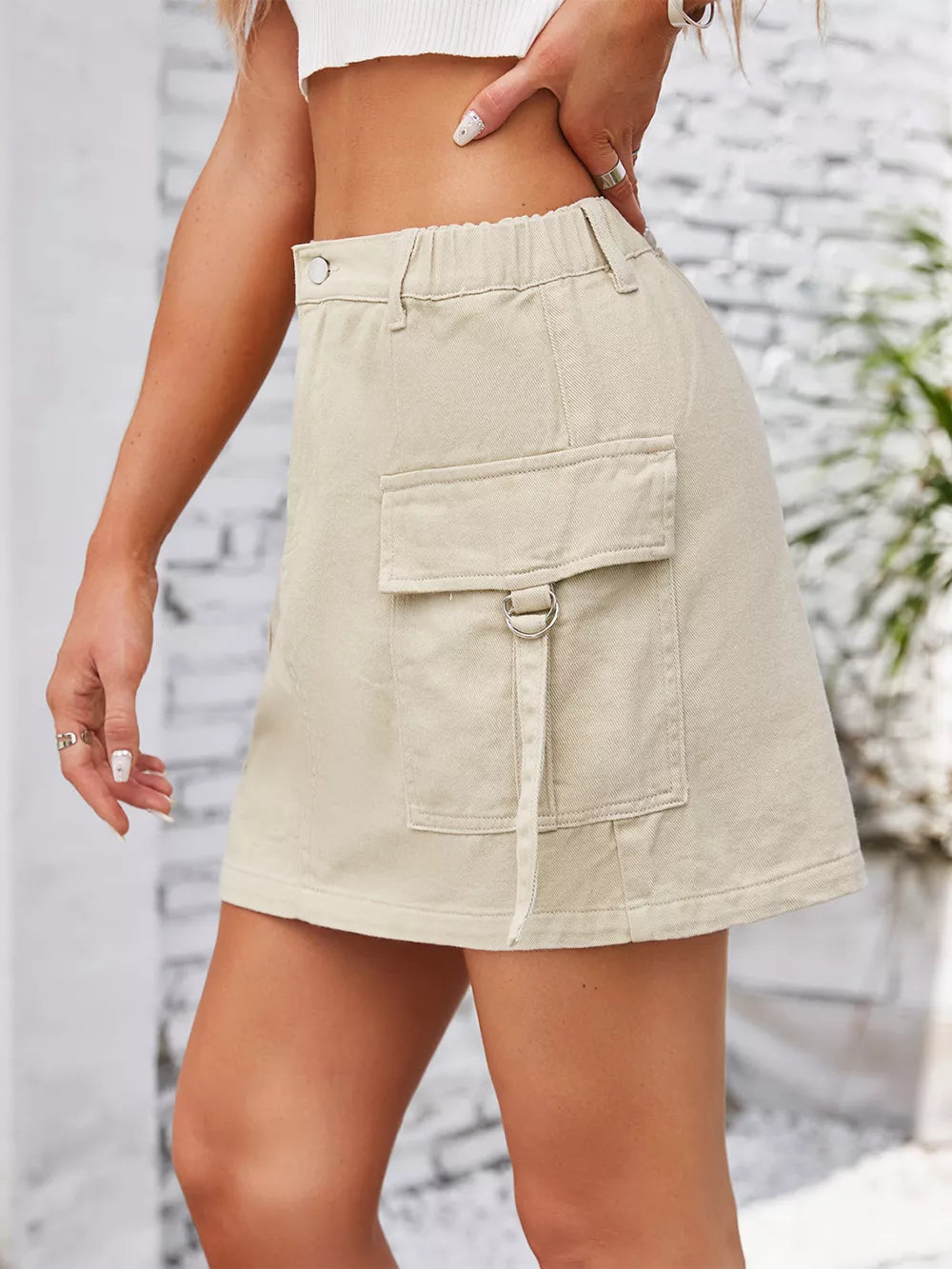 Beige denim cargo skirt with elastic waist and D-ring detail on pocket.