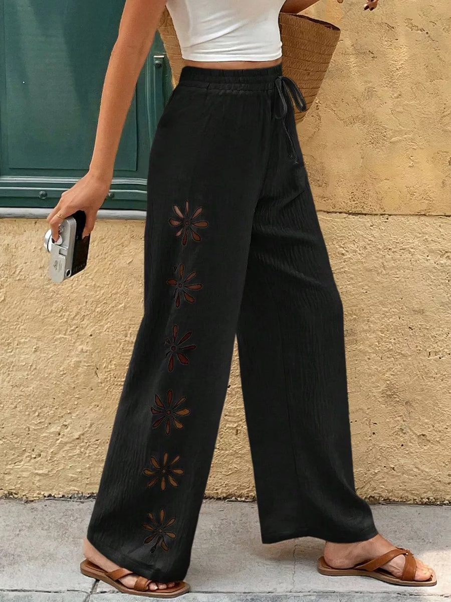 Black wide-leg pants with floral cutouts and drawstring waist