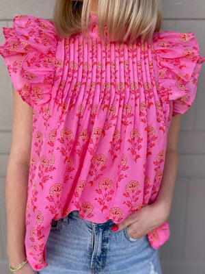 Pink floral print blouse with ruffled flutter sleeves and smocked bodice.