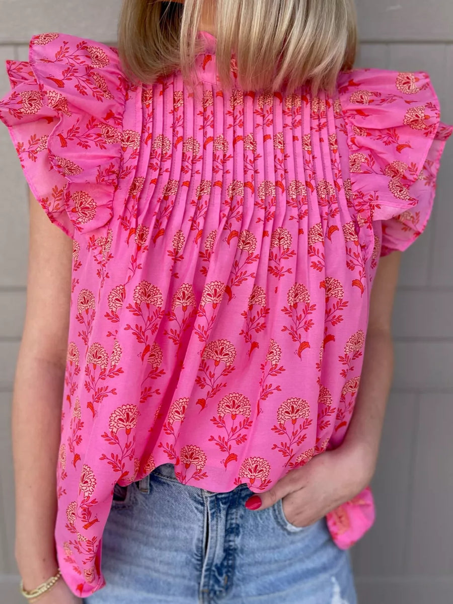 Pink floral print blouse with ruffled flutter sleeves and smocked bodice.
