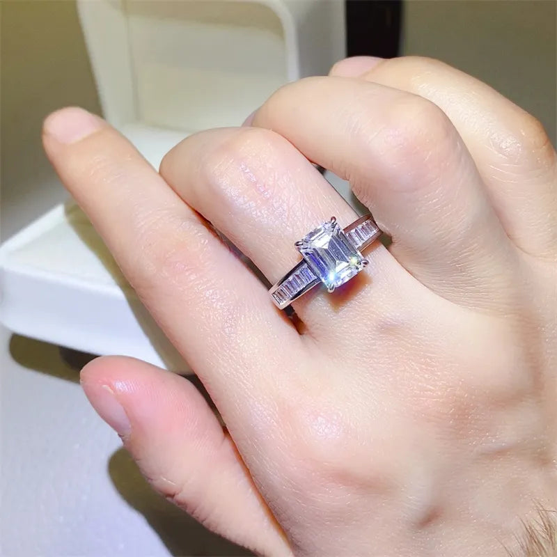 Emerald cut moissanite ring with baguette accents in silver sterling.