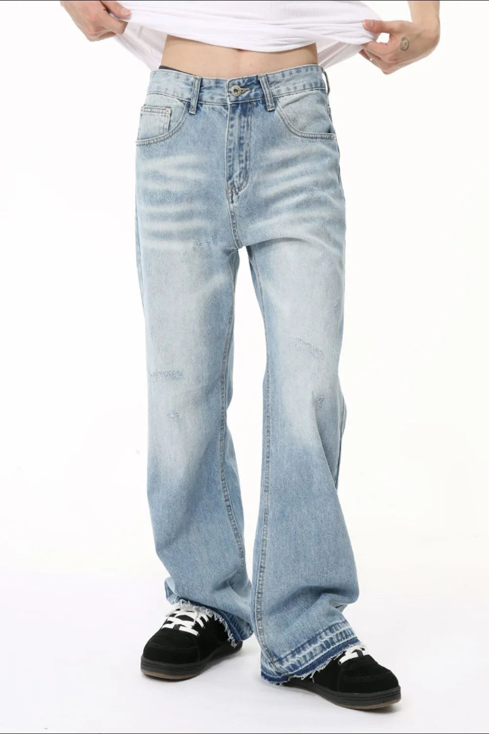 Baggy distressed denim jeans in medium wash with raw hem detail and a relaxed fit.