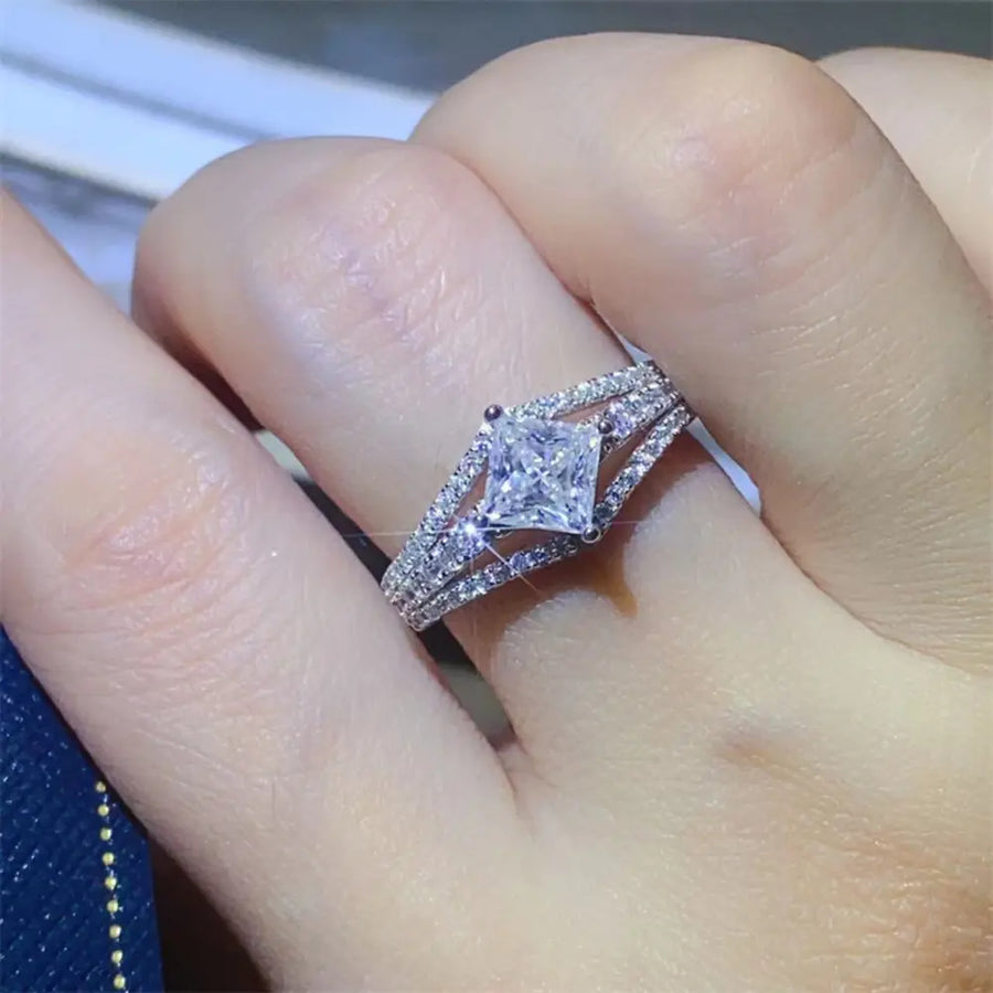 Princess cut moissanite ring in silver with a split shank band and pave accents.