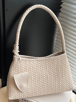 Off-white woven shoulder bag with braided strap and leather fob detail.