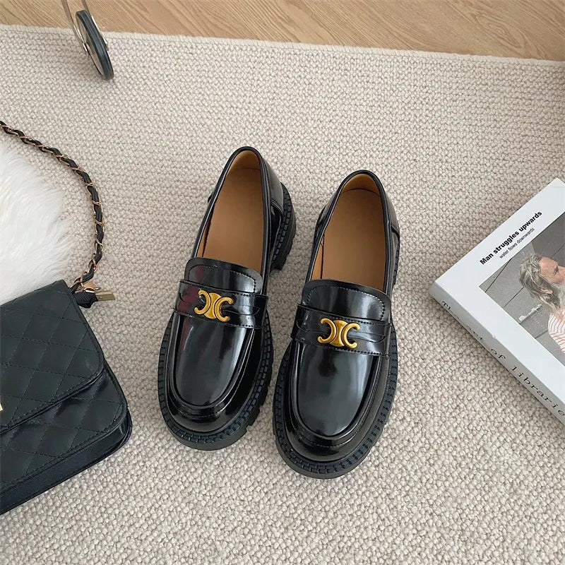 Black patent leather loafers with chunky sole and gold buckle detail.