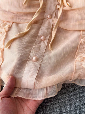 Watermelon pink maternity blouse with pearl buttons, ruffled trim, and tie detail.