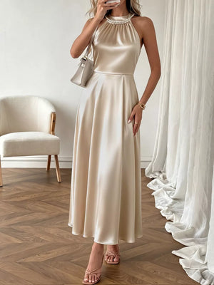 Elegant champagne satin midi dress with pearl halter neckline and A-line skirt.