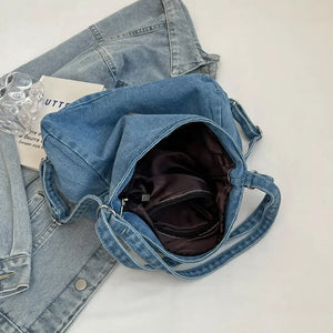 Medium wash denim hobo bag with leatherette patch and open main compartment.