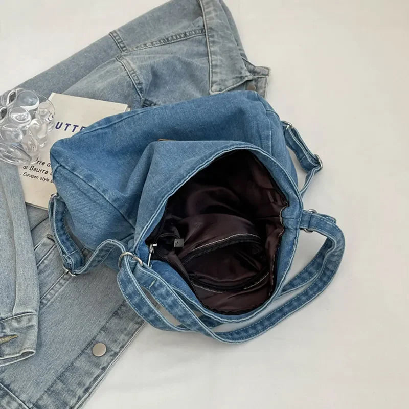 Medium wash denim hobo bag with leatherette patch and open main compartment.
