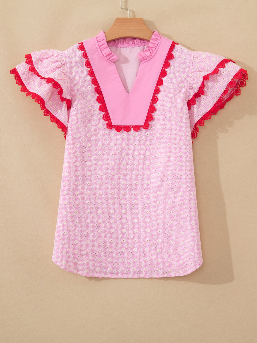 Pink eyelet embroidered blouse with flutter sleeves and red lace trim.