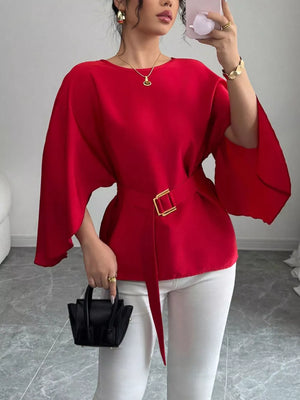Red belted blouse with batwing sleeves and gold buckle detail.