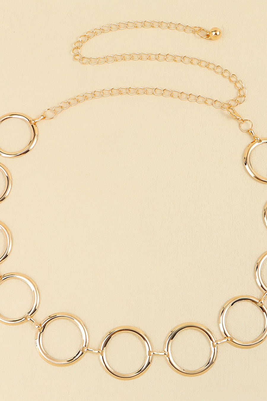 Gold geometric circle waist chain with a delicate link chain and clasp closure.