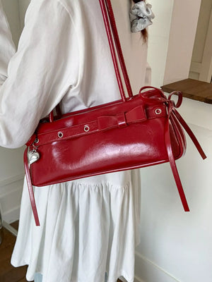 Red patent leather shoulder bag with bow detail and heart charm