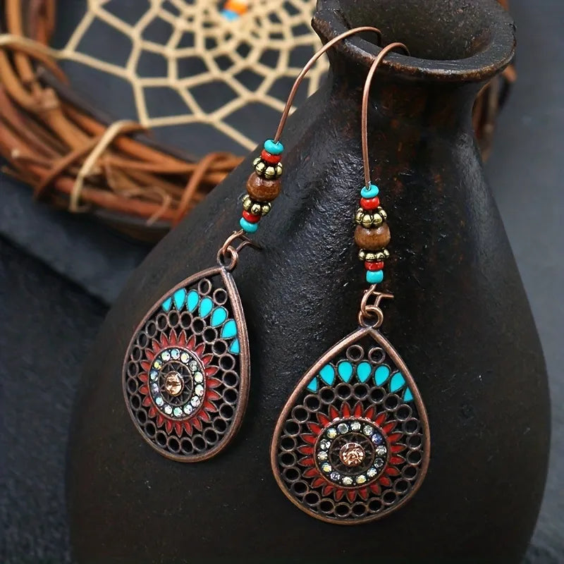 Bohemian mandala drop earrings in copper with turquoise and red accents, featuring intricate metalwork and beads.