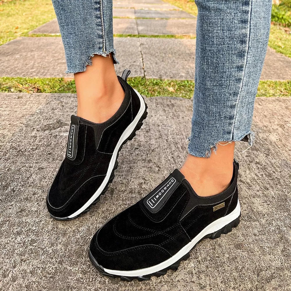Black suede-like round toe slip-on sneakers with white soles and "OUTDOOR" detail.