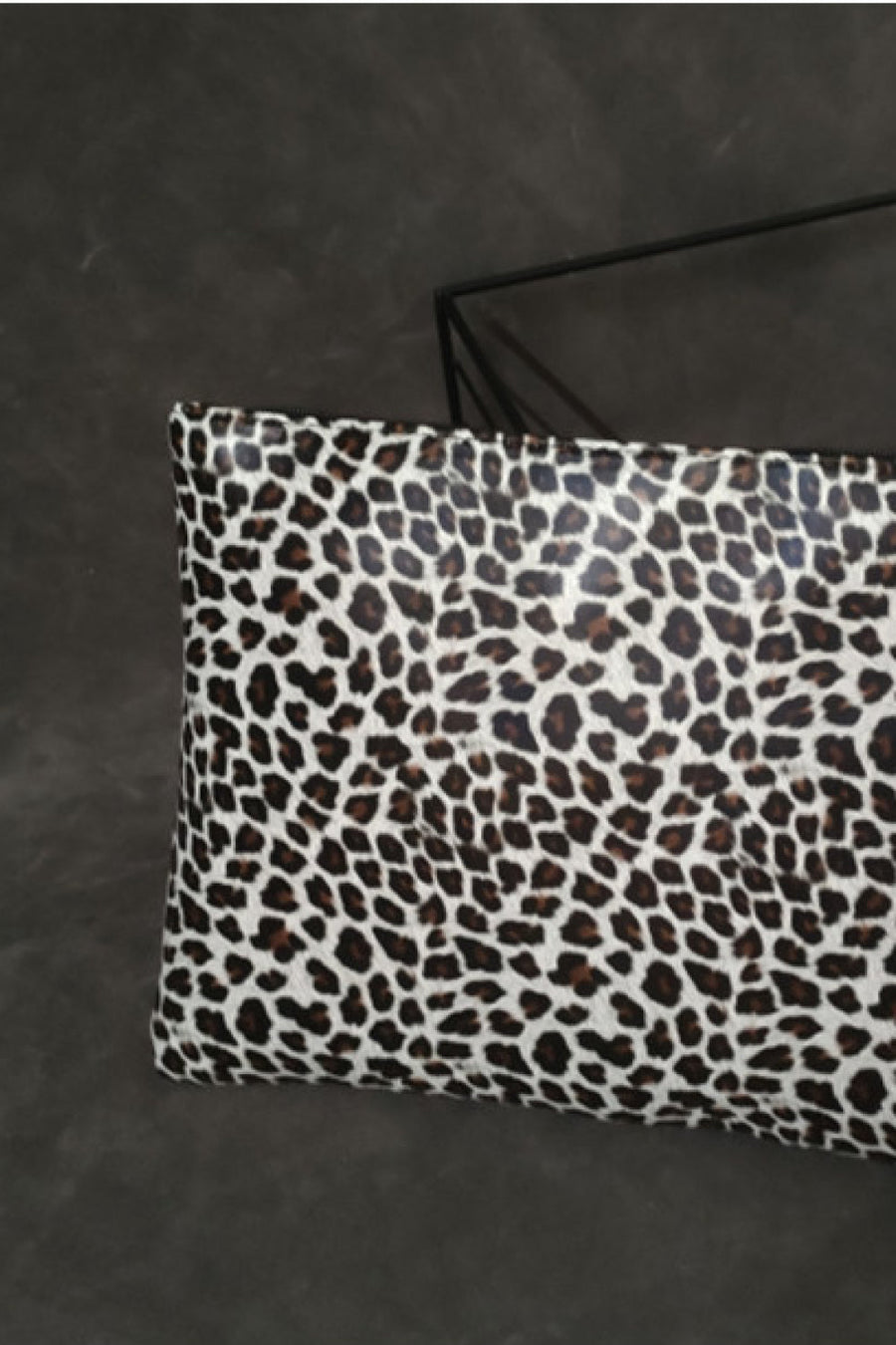 Leopard print zip-top clutch bag with bold animal print pattern.
