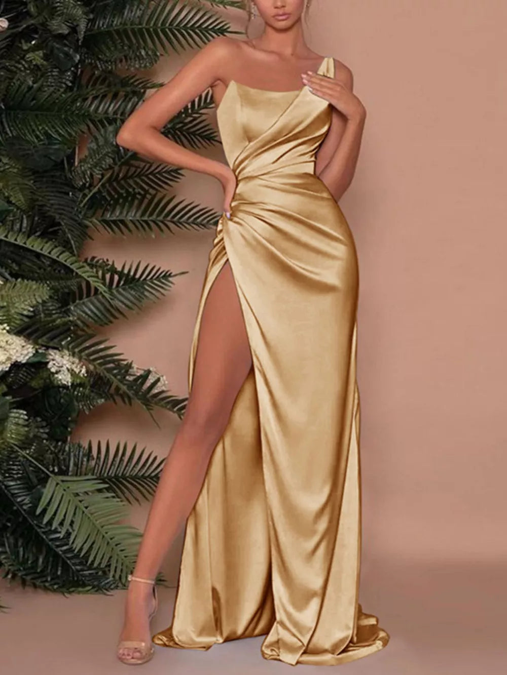 Gold one-shoulder ruched maxi dress with a high slit and satin finish.