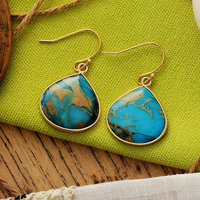 Teardrop turquoise and gold dangle earrings with unique blue and tan stone patterns.