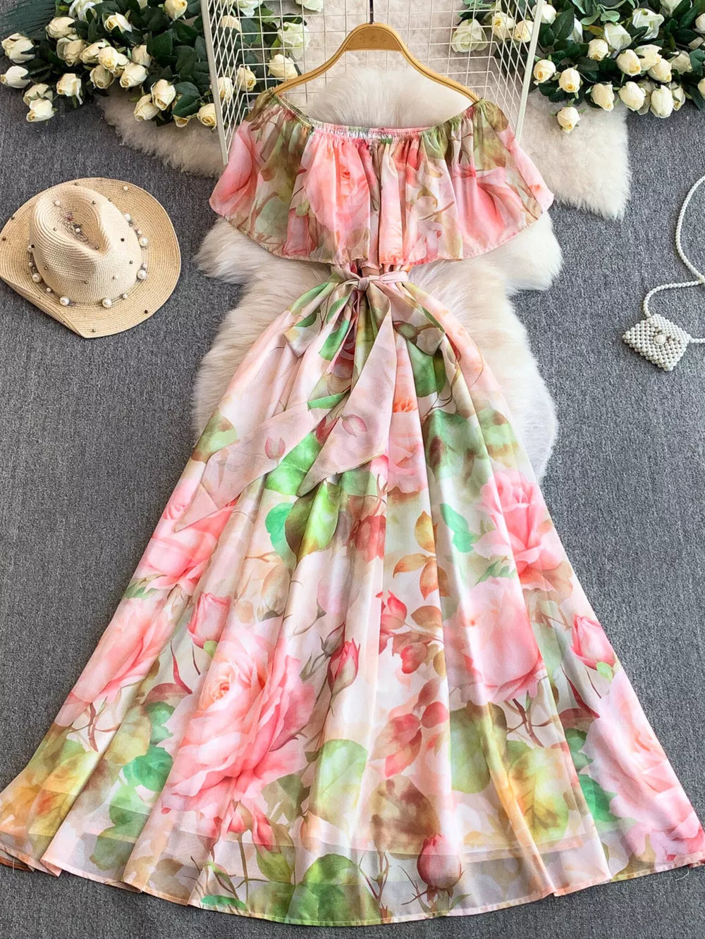 Botanical off-shoulder A-line dress in light pink with floral print, belted waist, and flowing skirt.