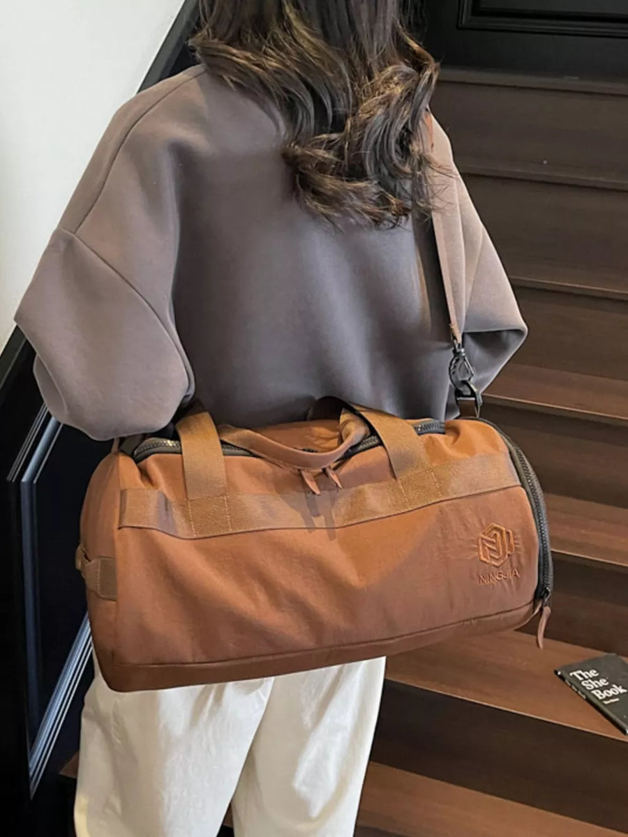 Brown Oxford cloth duffel bag with carry handles and adjustable strap, shown on a woman.