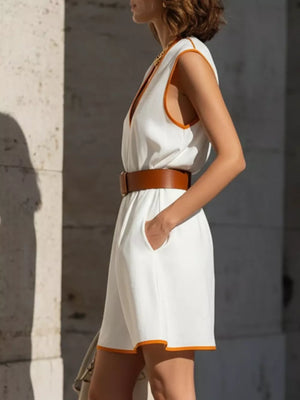 White sleeveless mini dress with deep V-neck and orange trim, cinched with a brown belt.