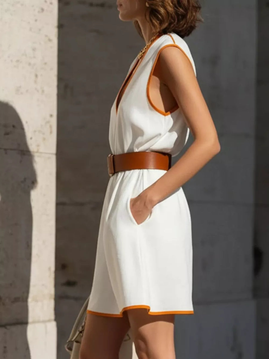 White sleeveless mini dress with deep V-neck and orange trim, cinched with a brown belt.