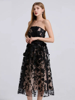 Black strapless midi dress with intricate floral applique and sheer overlay.