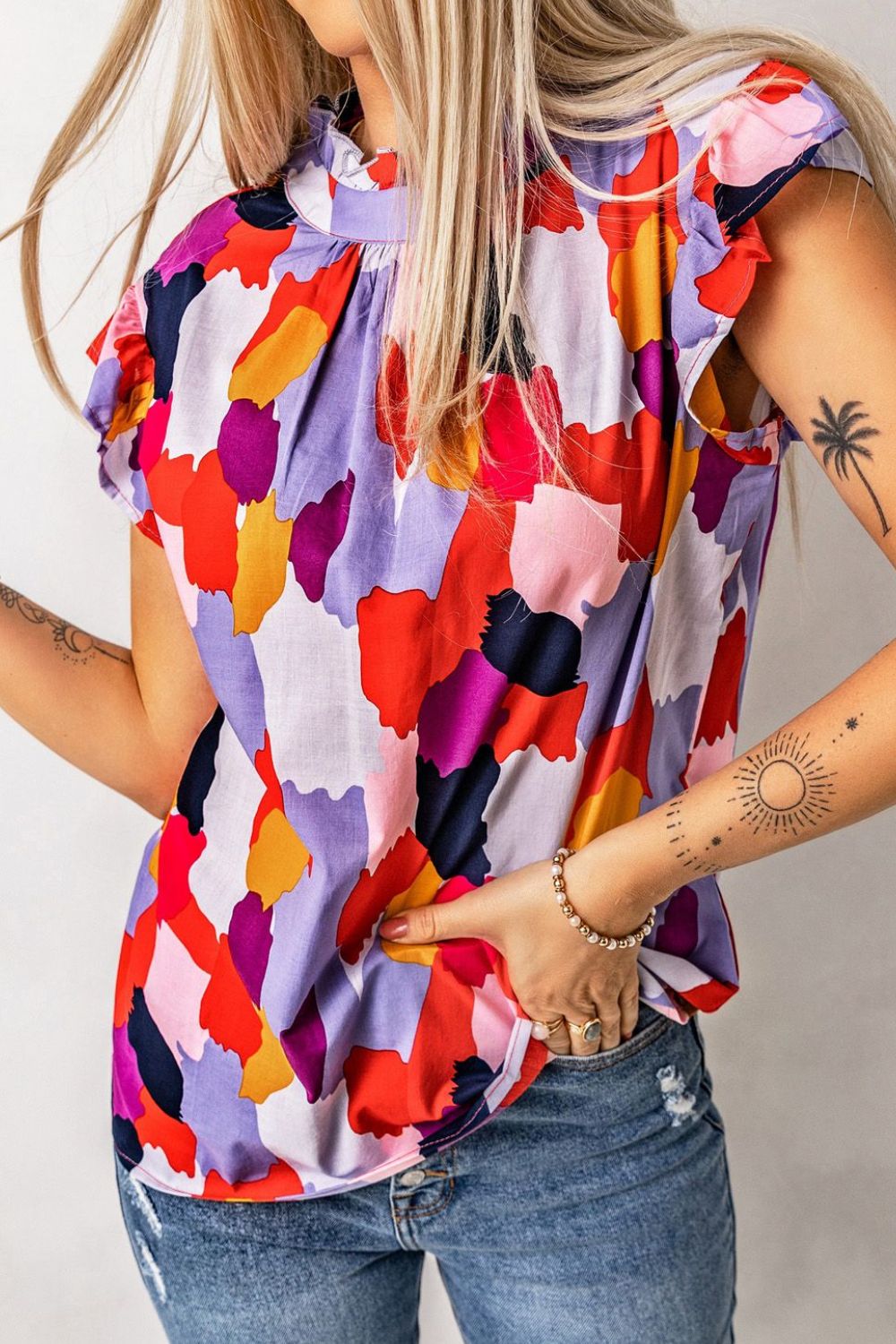 Abstract brushstroke ruffle neck blouse with short sleeves in a colorful print.