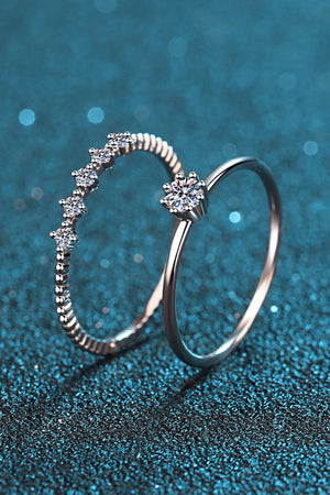 Silver rings set with moissanite stones, one with a starburst design, the other with a celestial row.