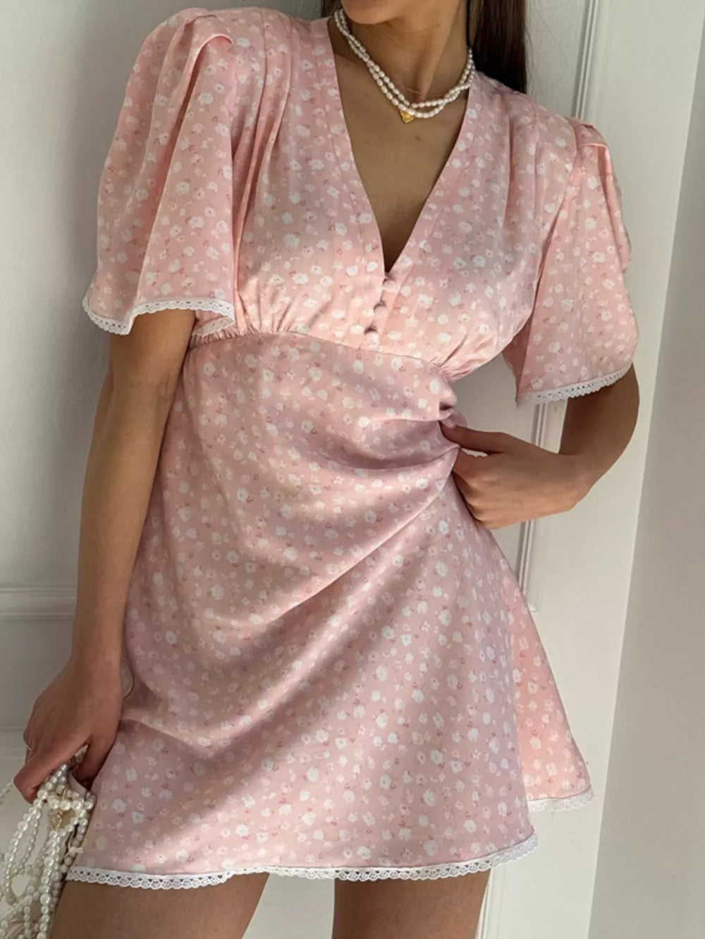 Pink floral print mini dress with v-neck, puff sleeves, and lace trim.