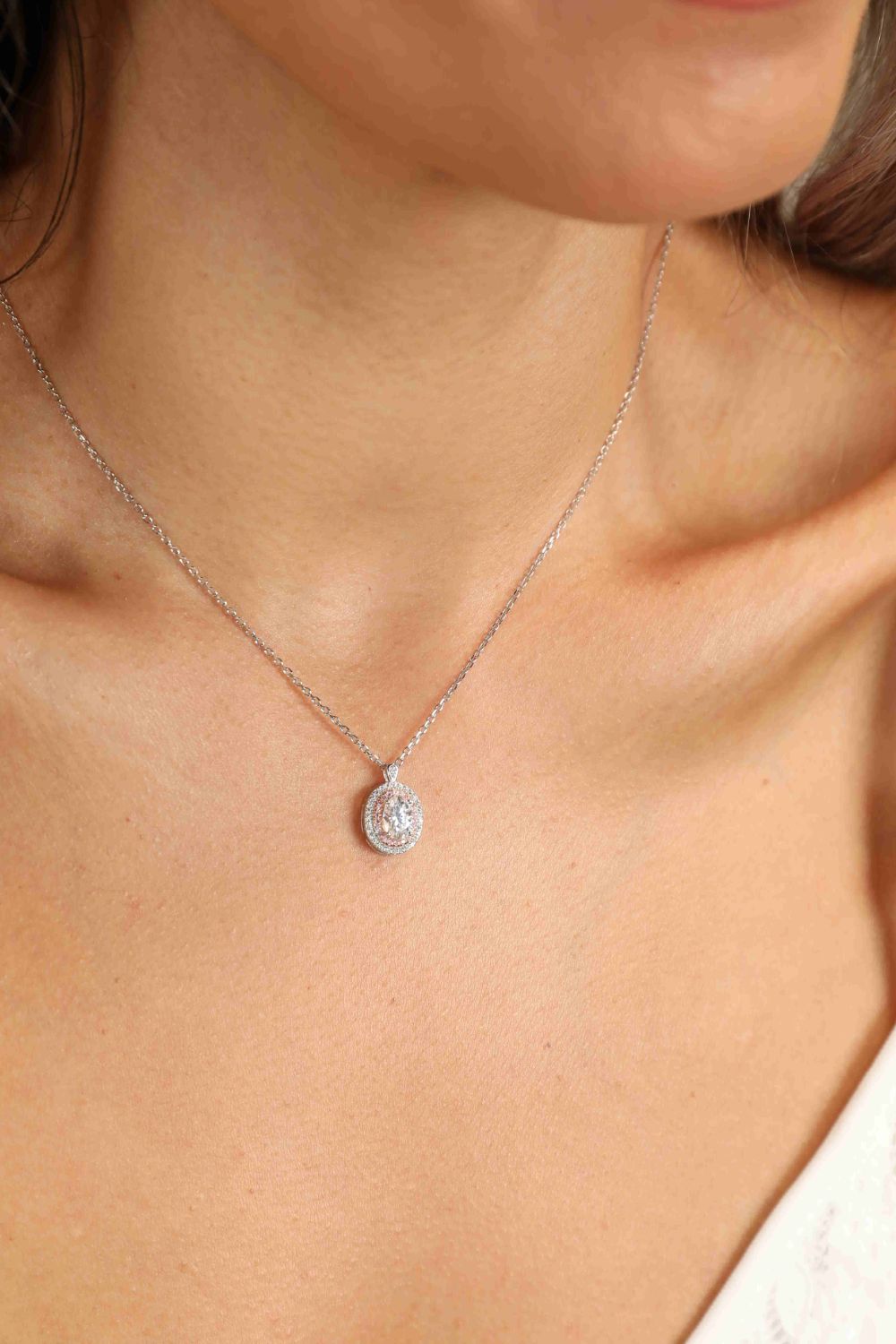 Silver moissanite halo pendant necklace with a delicate chain.