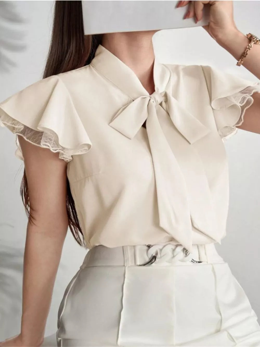 Beige tie-neck blouse with ruffle sleeves and lace trim.