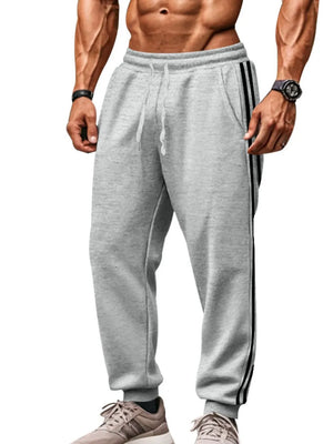 Gray joggers with black athletic stripes on the side, drawstring waist, and cuffed ankles.