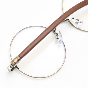 Round frame glasses with clear lenses, silver metal rims, and brown acetate temples with decorative detail.