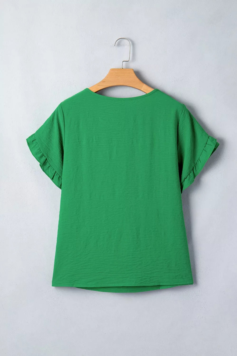 Green polyester short sleeve blouse with ruffle trim details.