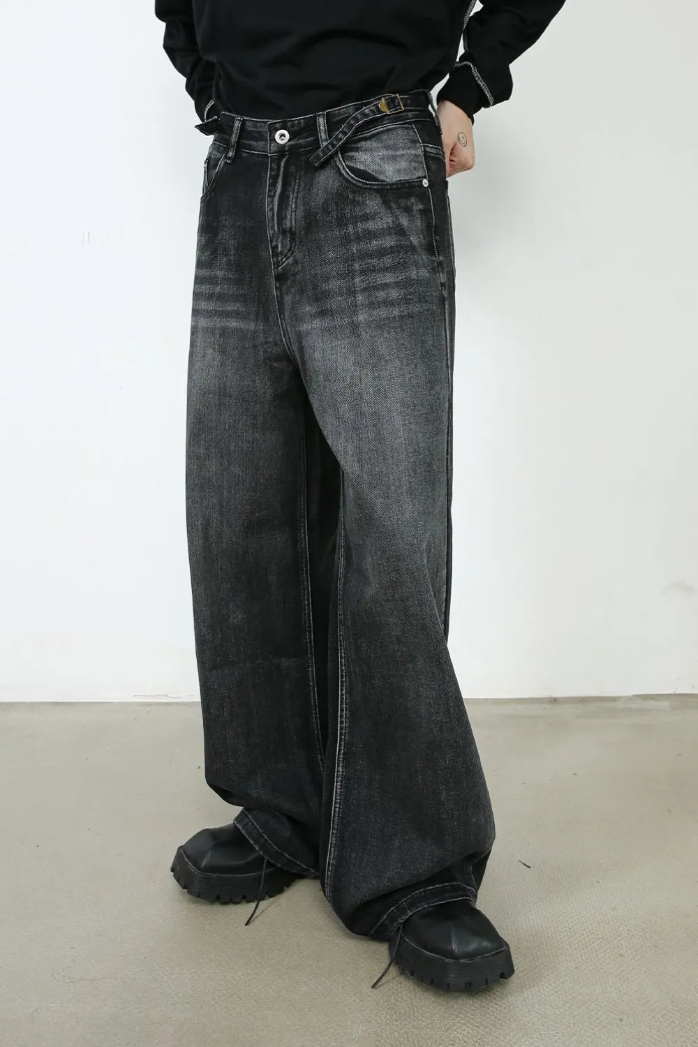 Dark wash denim trousers with a wide flare leg and unique belted waist detail.