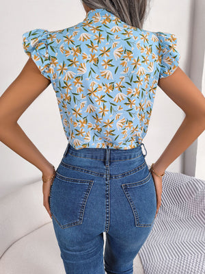 Light blue floral blouse with ruffle sleeves and mock neck, paired with denim jeans.
