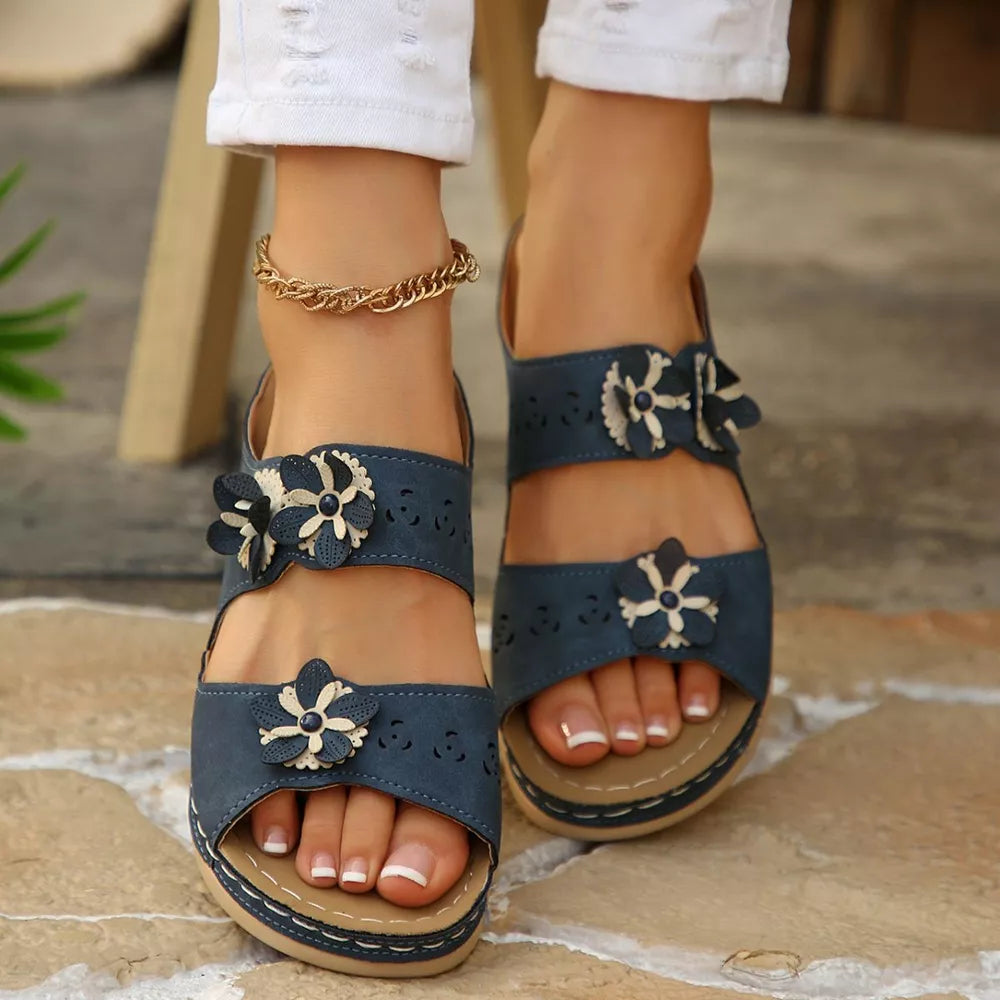 Navy blue sandals with floral appliqués and cutouts, featuring a comfortable mid-heel.
