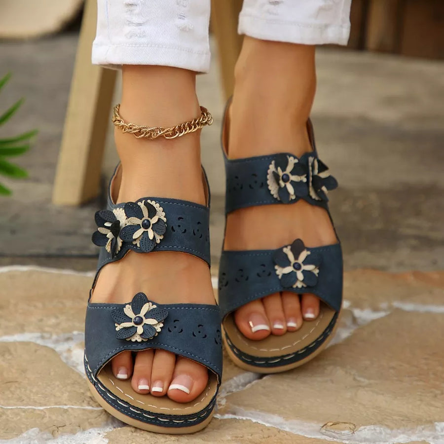 Navy blue sandals with floral appliqués and cutouts, featuring a comfortable mid-heel.