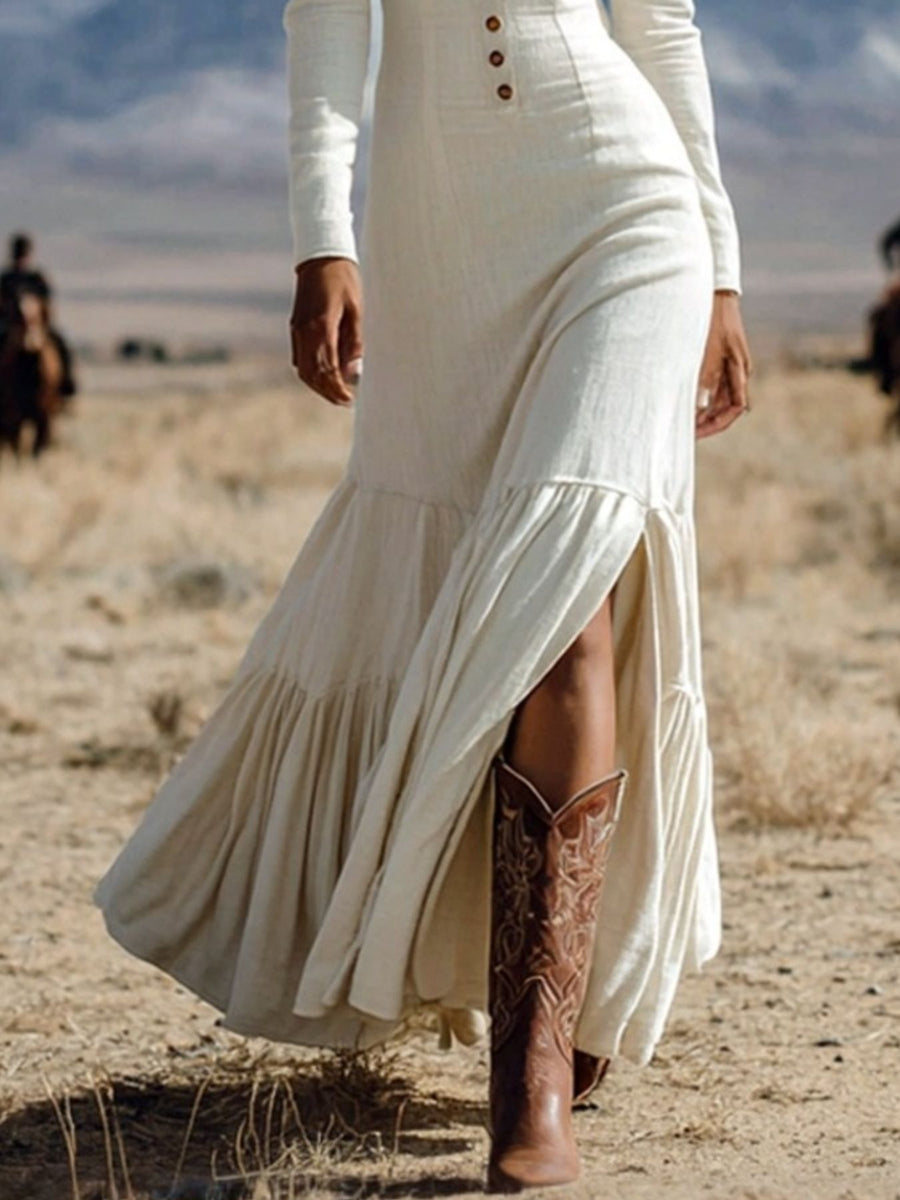White long sleeve maxi dress with button detail and thigh slit, styled with cowboy boots.