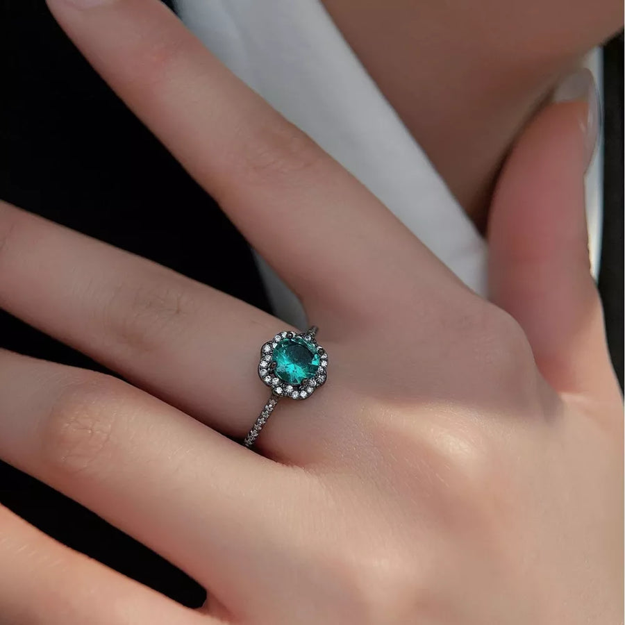 Elegant sterling silver ring with a teal zircon center and halo of small clear stones.