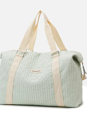Light green waffle-weave weekend bag with cream straps and silver hardware.