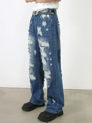 Oversized ripped denim jeans in medium wash with raw edge detail and distressed accents.