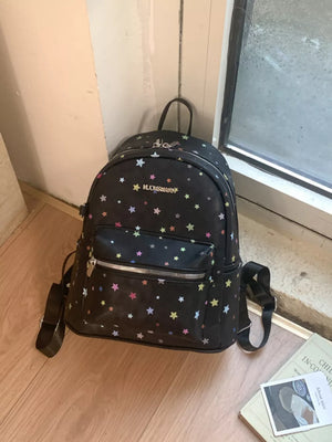 Black mini backpack with colorful star print and front zip pocket.
