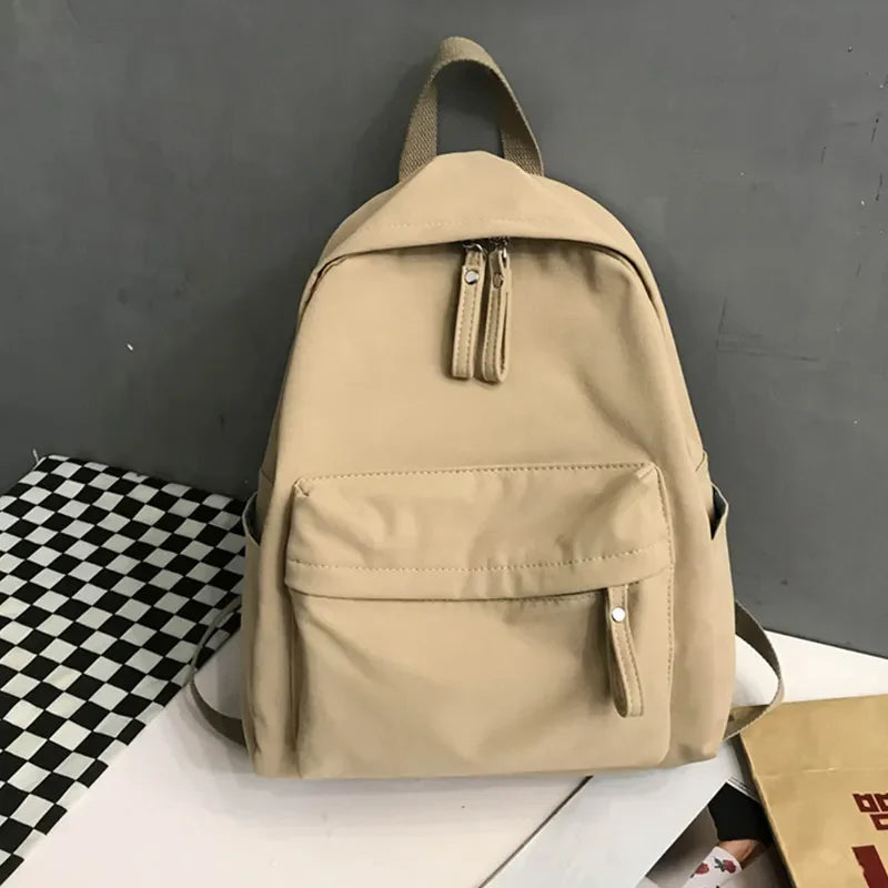 Khaki canvas school backpack with dual front pockets and zippers.