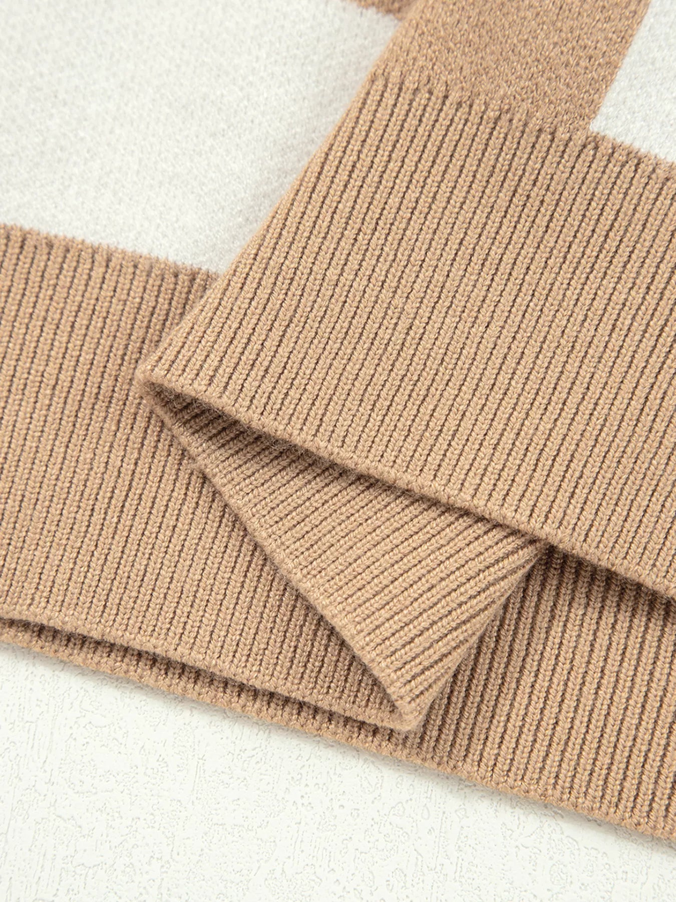 Camel drop shoulder sweater with ribbed knit sleeves and a checkered pattern detail.