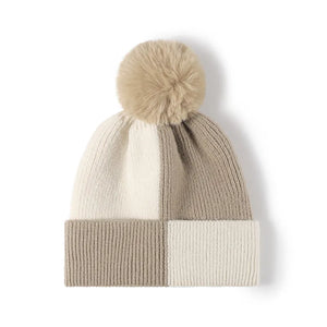 Colorblock knit beanie with a fuzzy pom in beige and cream.