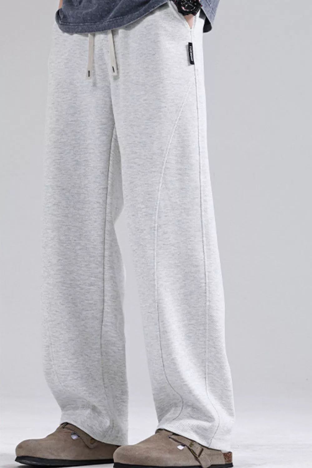 Men's light gray loose fit sweatpants with drawstring waist and curved seam detail.