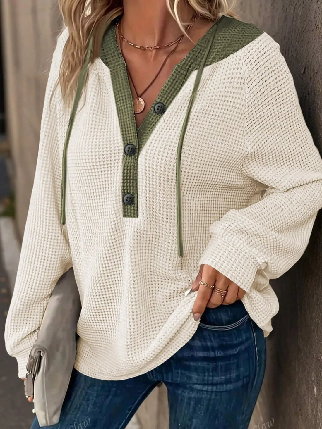 Beige waffle-knit hoodie with green contrast trim and button detail.